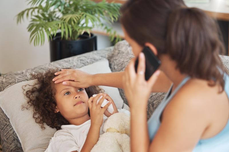 a mother holding the forehead of her sick daughter